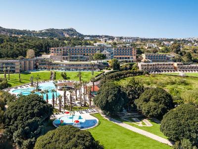 Grande resort con piscina, giardino e prati vicino a colline sotto il sole.