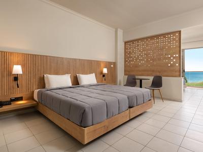 Camera d'hotel moderna con letto matrimoniale, scrivania e vista sul mare.