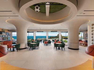 Area reception di un hotel moderna e luminosa con vista sul mare e sedute eleganti.