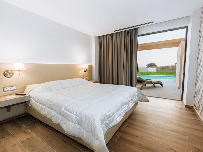 Camera moderna con letto matrimoniale e accesso a una terrazza con vista piscina.