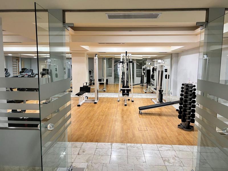 Sala fitness moderna con pavimento in legno e attrezzi per allenamento di forza e resistenza.