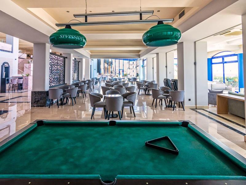 Interno di un hotel con tavolo da biliardo e area pranzo con tavoli e sedie.