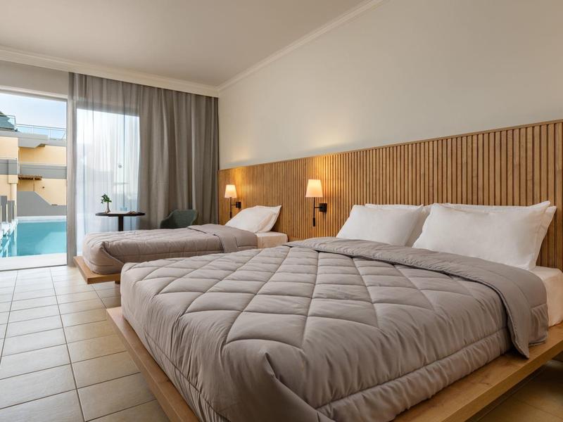 Camera d'hotel moderna con due letti e vista su una piscina attraverso una porta scorrevole in vetro.