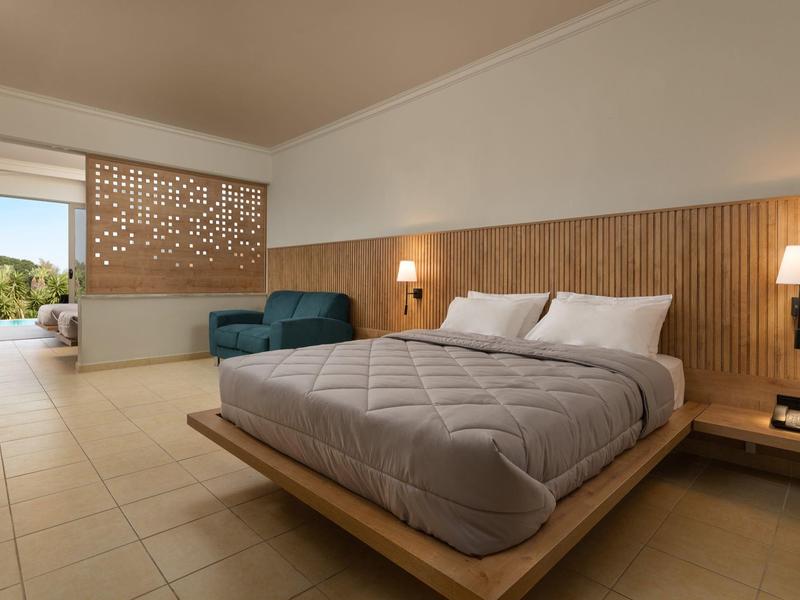 Camera d'hotel moderna con letto matrimoniale, divano e terrazza con vista sulla piscina.