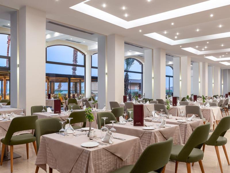 Ristorante moderno con tavoli elegantemente apparecchiati e sedie verdi accanto a grandi finestre.