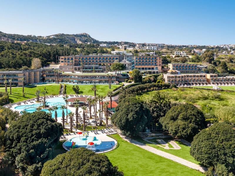 Grande resort con piscina, giardino e prati vicino a colline sotto il sole.