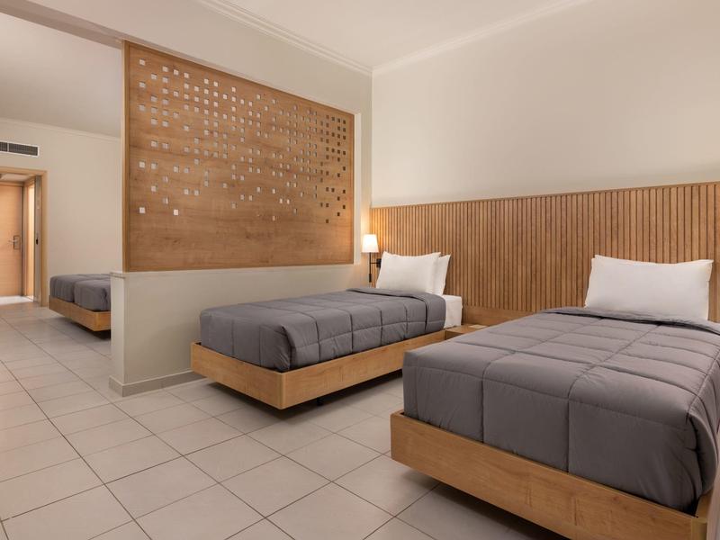 Due letti singoli in una stanza d'hotel pulita con pannelli di legno e lampade da parete.