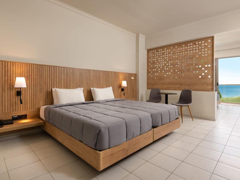 Camera d'hotel moderna con letto matrimoniale, scrivania e vista sul mare.