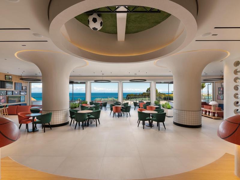 Area reception di un hotel moderna e luminosa con vista sul mare e sedute eleganti.