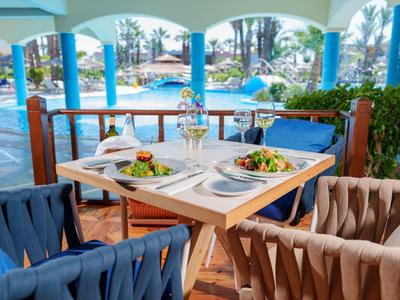 Terrace table with two salad plates and drinks in front of a hotel pool.