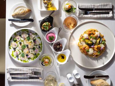 Stůl prostřený s čerstvým salátem, předkrmem, chlebem, olivami a nápoji v restauraci.