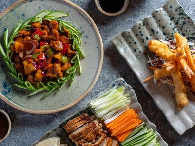 Various Asian dishes with grilled meat, fresh vegetables, and fried shrimp.
