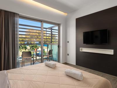 Camera d'hotel moderna con letto matrimoniale, balcone e TV a muro.