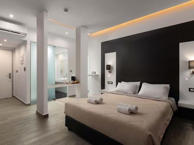 Camera moderna con copriletto beige, illuminazione soffusa e pavimento in legno in una camera d'hotel.