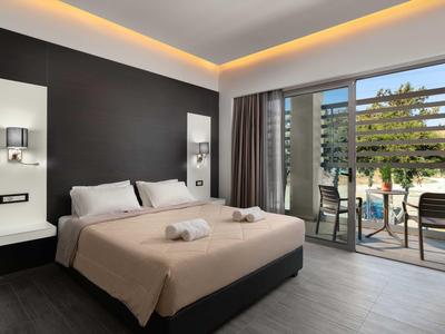 Camera d'hotel moderna con letto matrimoniale, parete scura e balcone con vista sulla piscina.