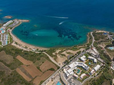 Veduta aerea di un resort sulla spiaggia con sabbia, mare turchese e vegetazione circostante.