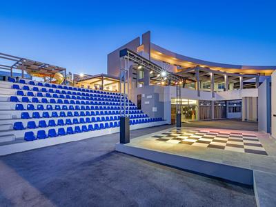 Zona exterior moderna con gradas y pista de baile en un complejo hotelero al atardecer.
