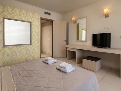 Camera d'hotel moderna con letto, asciugamani, TV, scrivania e specchio.