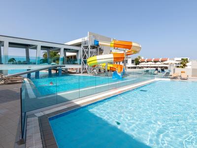 Piscina esterna con scivoli d'acqua e cielo sereno in un hotel resort.