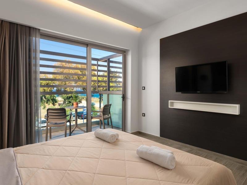 Camera d'hotel moderna con letto matrimoniale, balcone e TV a muro.