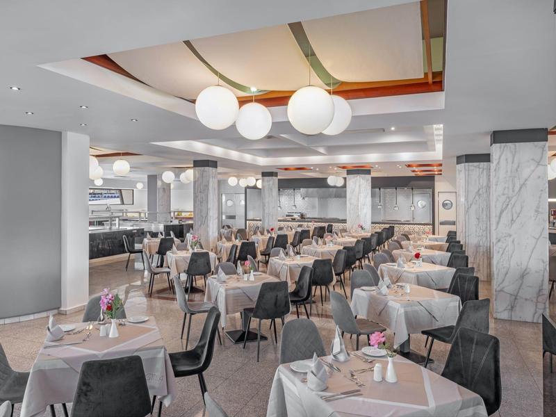 Sala da pranzo moderna dell'hotel con tavoli apparecchiati per gli ospiti, illuminazione elegante e sedute confortevoli.