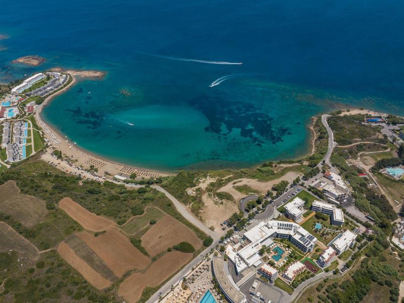 Veduta aerea di un resort sulla spiaggia con sabbia, mare turchese e vegetazione circostante.