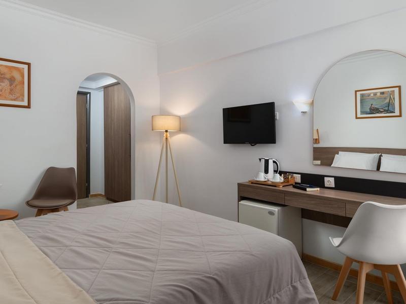 Camera d'hotel accogliente con letto, scrivania, TV, sedia e arredamento moderno.