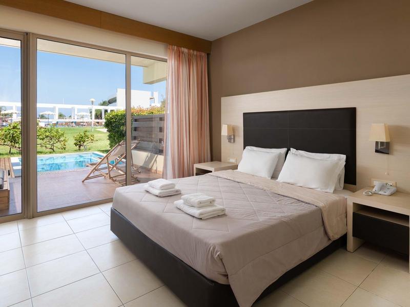 Camera d'hotel moderna con letto matrimoniale, comodini e vista piscina attraverso porte scorrevoli in vetro.