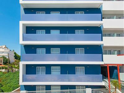 Edificio de hotel moderno con fachada azul y tumbonas junto a una piscina