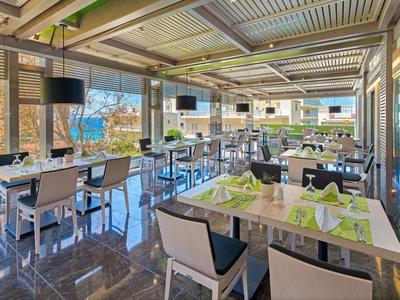 Bright, modern hotel restaurant with green napkins, large windows, and outdoor views.