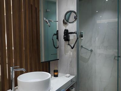 Bagno moderno con lavabo rotondo, rivestimento in legno e doccia in vetro.
