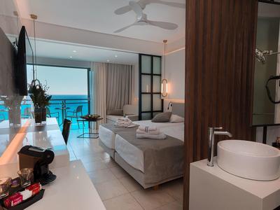 Camera d'hotel moderna con letto matrimoniale, vista mare, balcone e bagno aperto.