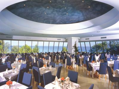 Grande sala da pranzo moderna con finestra circolare sul soffitto e molti tavoli apparecchiati.