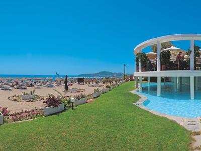 Plage avec parasols, transats et un pavillon rond à côté d'une piscine sous un ciel clair.