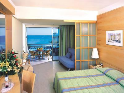 Hell eingerichtetes Hotelzimmer mit Balkon und Meerblick.