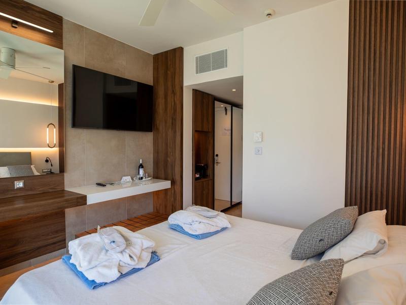 Camera da letto con letto matrimoniale, mobili in legno e TV a schermo piatto, stanza d'hotel moderna.