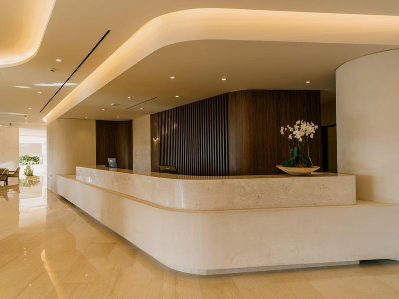 Hall dell'hotel moderno con lungo bancone curvo per la reception e decorazioni minimaliste.