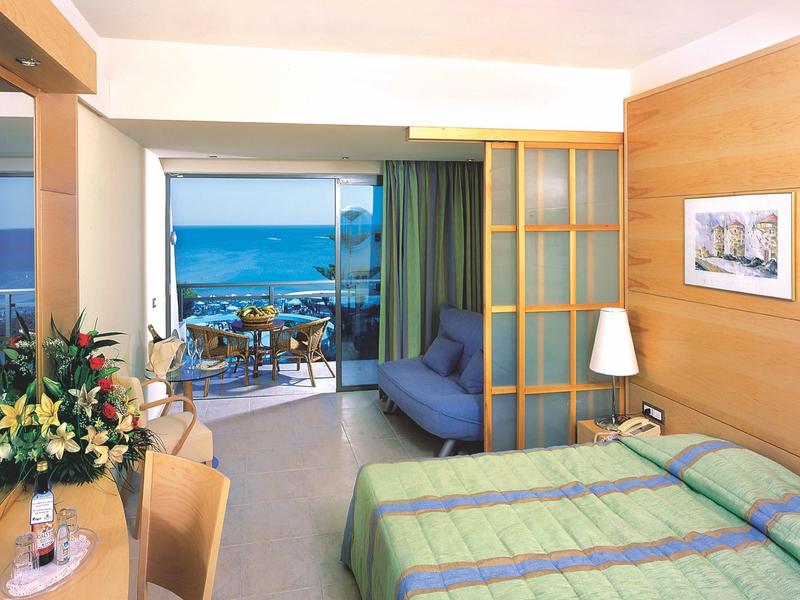 Hell eingerichtetes Hotelzimmer mit Balkon und Meerblick.