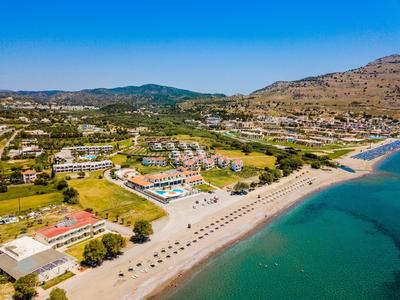 Kurort nadmorski z basenem, leżakami i parasolami przy turkusowym morzu i zalesionych wzgórzach.