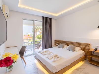 Nowoczesny pokój hotelowy z podwójnym łóżkiem, balkonem i dekoracją kwiatową.