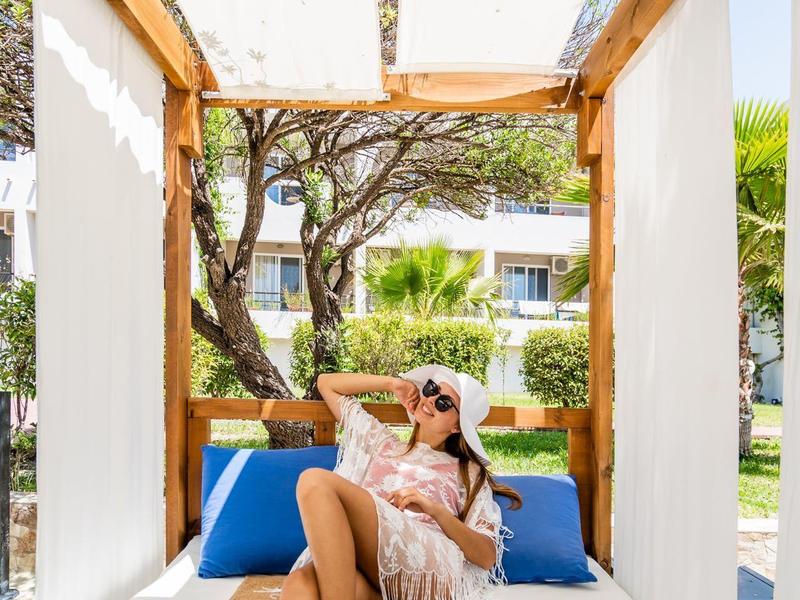 Kobieta relaksująca się na nowoczesnej zewnętrznej leżance pod drewnianą konstrukcją z osłoną przeciwsłoneczną