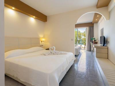 Hotel room with double bed, lighting accents, and balcony view with plants.