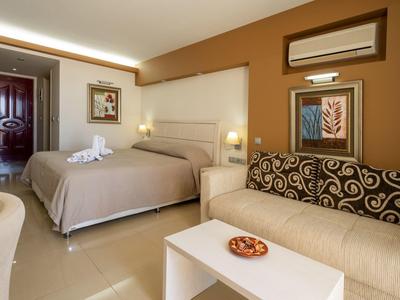 Modern hotel room with double bed, sofa, table, and decorative wall art.