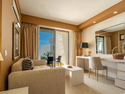 View of a beach hotel with pool, sun umbrellas, and mountains in the background.