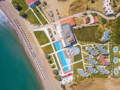 Aerial view of a beach resort with pools, sunbeds, and close to the water.