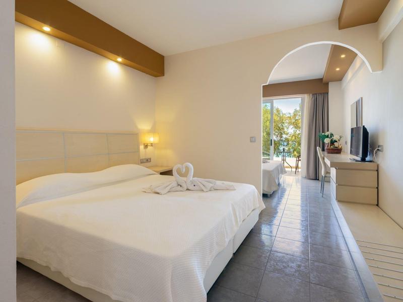 Hotel room with double bed, lighting accents, and balcony view with plants.