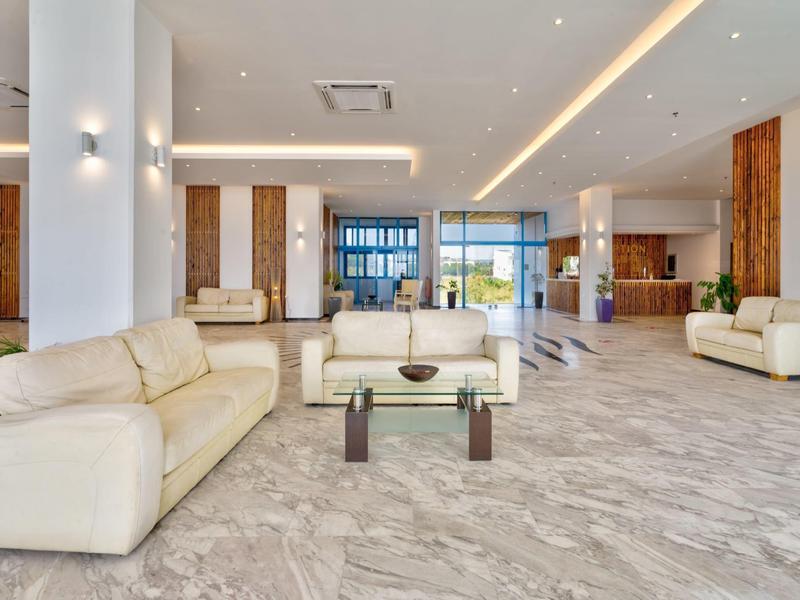 Bright modern hotel lobby with white sofas and large marble floor.