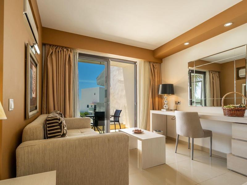 View of a beach hotel with pool, sun umbrellas, and mountains in the background.