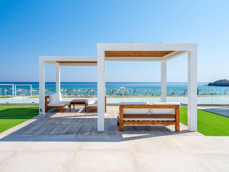 Modern pavilion with wooden furniture overlooking the sea on a sunny day.