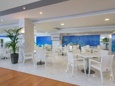 Moderner, heller Speisesaal mit weißen Möbeln und Pflanzen in einem Hotel.